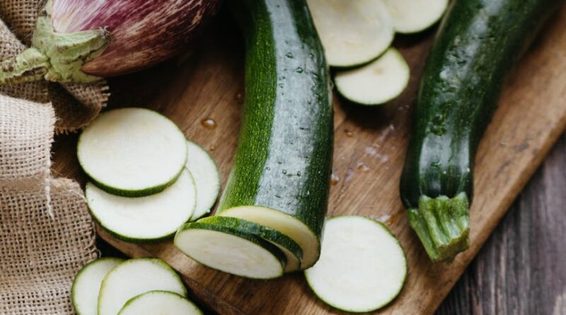 sliced zucchini eggplant and lettuce on a wooden chopping board